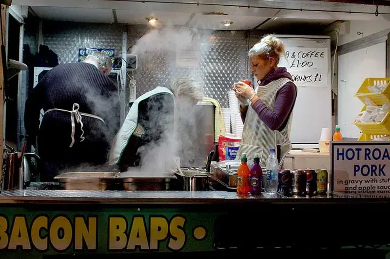 A hot food van serving bacon baps, steam rising from the griddle