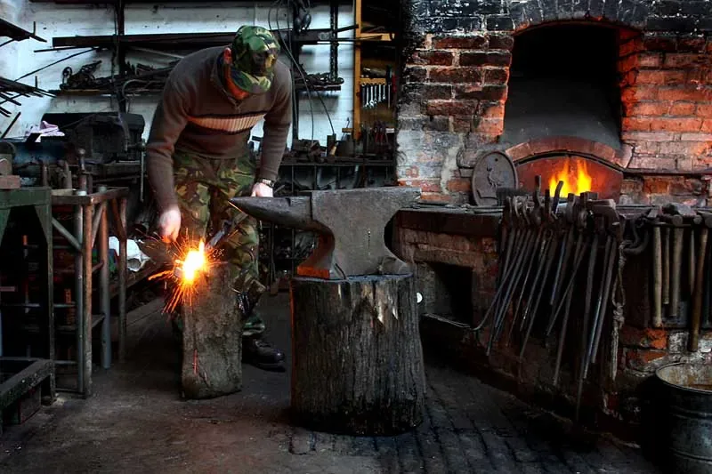 A blacksmith working at the forge, sparks coming off the anvil