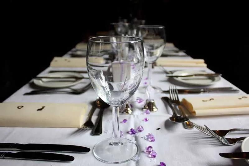 A table laid for dinner, glassware and cutlery picked out against the dark